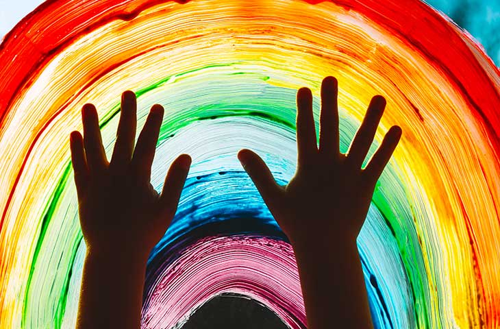 child's hands facing up to rainbow painting