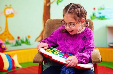 girl in wheelchair playing with developing toy