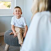 young patient smiling on stool with provider 